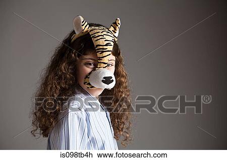 Stock Image - Young girl wearing tiger mask. Fotosearch