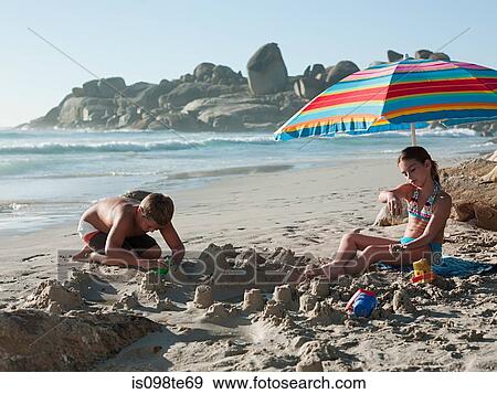 Boy and girl making sandcastles on beach View Large Photo Image Stock Photo - Boy and girl making sandcastles on beach. Fotosearch