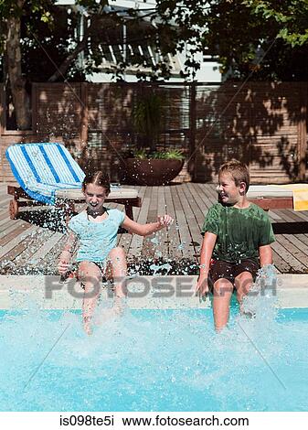 Stock Image - Boy and girl splashing in swimming pool. Fotosearch