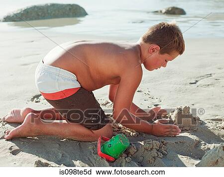 Boy making sandcastles on a beach View Large Photo Image Stock Image - Boy making sandcastles on a beach. Fotosearch