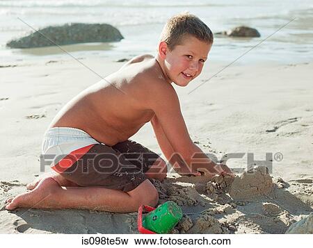 Boy making sandcastles on a beach View Large Photo Image Stock Photo - Boy making sandcastles on a beach. Fotosearch