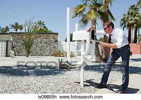 Stock Image - Man looking into mailbox. Fotosearch