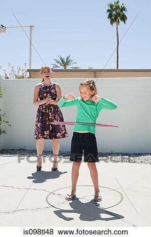 Mother watching daughter with hoola hoop View Large Photo Image Stock Photo - Mother watching daughter with hoola hoop. Fotosearch