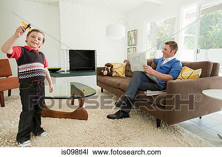 Young boy playing with toy aeroplane, father reading newspaper View Large Photo Image Stock Image - Young boy playing with toy aeroplane, father reading newspaper. Fotosearch