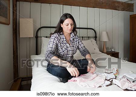 Expectant mother looking at baby clothes View Large Photo Image Picture - Expectant mother looking at baby clothes. Fotosearch