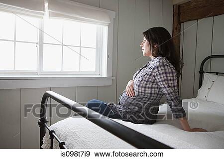 Expectant mother sitting on bed View Large Photo Image Stock Photo - Expectant mother sitting on bed. Fotosearch