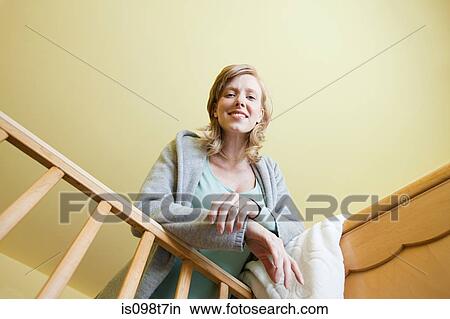 Picture - Woman looking in to crib. Fotosearch