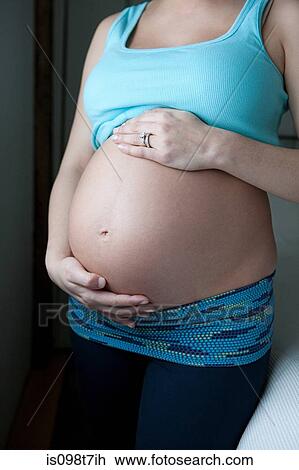 Stock Image - Woman showing pregnancy bump. Fotosearch