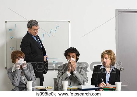Stock Image - Businessman blowing nose in office. Fotosearch