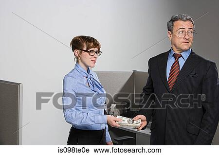 Stock Image - Businessman handing over money to businesswoman. Fotosearch