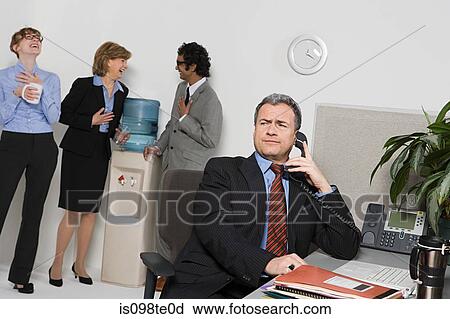 Businessman on telephone with people gossiping by water cooler View Large Photo Image Stock Image - Businessman on telephone with people gossiping by water cooler. Fotosearch