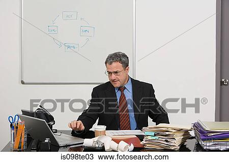 Stock Image - Businessman working at desk. Fotosearch