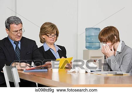 Stock Image - Businesswoman blowing nose in office. Fotosearch