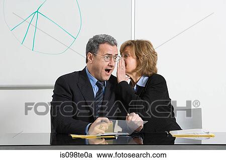 Stock Image - Businesswoman whispering secret to businessman. Fotosearch
