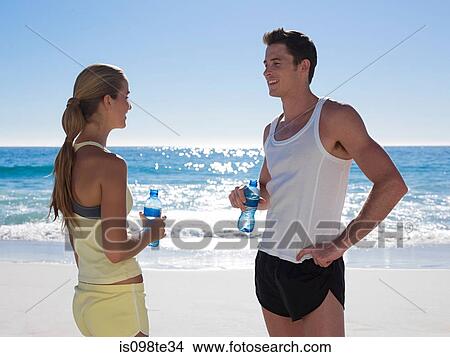 Young couple with bottles of water on beach View Large Photo Image Picture - Young couple with bottles of water on beach. Fotosearch