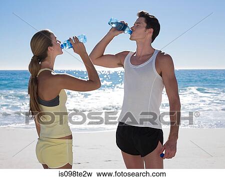 Young couple with bottles of water on beach View Large Photo Image Stock Photo - Young couple with bottles of water on beach. Fotosearch