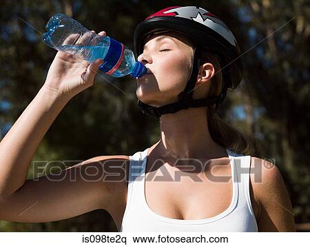 Young female cyclist drinking water View Large Photo Image Stock Photography - Young female cyclist drinking water. Fotosearch
