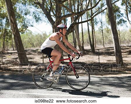 Stock Image - Young man cycling in forest. Fotosearch