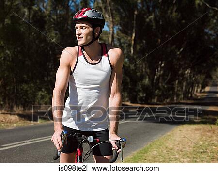 Stock Image - Young man cycling on road. Fotosearch