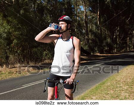 Young man cycling on road View Large Photo Image Stock Photo - Young man cycling on road. Fotosearch