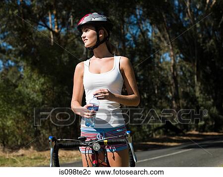 Stock Image - Young woman cycling on road. Fotosearch