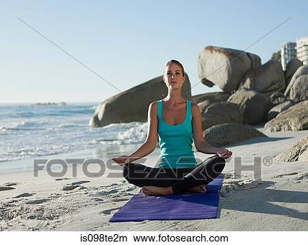 Picture - Young woman doing yoga on beach. Fotosearch