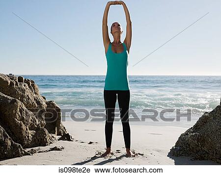 Stock Image - Young woman doing yoga on beach. Fotosearch