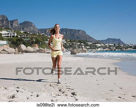Stock Image - Young woman jogging on beach. Fotosearch