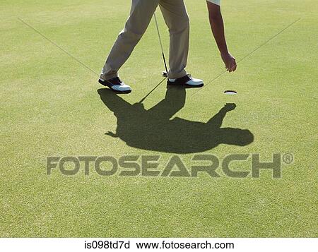 Stock Image - Man playing golf, picking up ball. Fotosearch