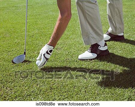 Stock Image - Man playing golf, picking up ball. Fotosearch