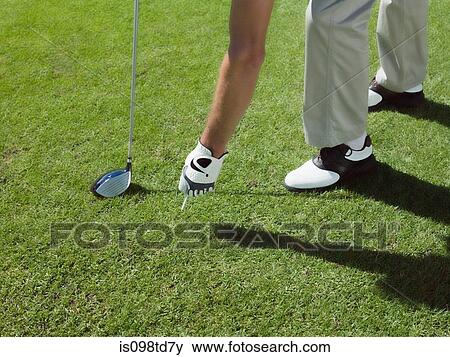 Stock Photo - Man playing golf, picking up ball. Fotosearch