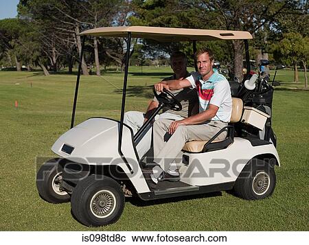 Stock Image - Two mature men in golf cart on golf course. Fotosearch