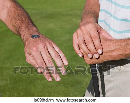 Picture - Two mature men playing golf together, tossing a coin. Fotosearch