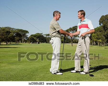 Two mature men shaking hands on golf course View Large Photo Image Stock Image - Two mature men shaking hands on golf course. Fotosearch