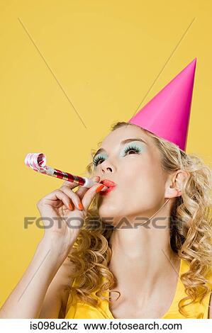 Young woman wearing party hat with party blower View Large Photo Image Stock Photo - Young woman wearing party hat with party blower. Fotosearch