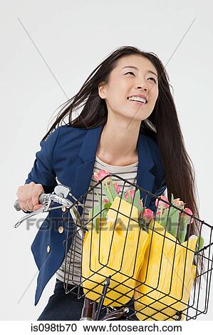 Woman riding bicycle with flowers in basket View Large Photo Image Stock Image - Woman riding bicycle with flowers in basket. Fotosearch