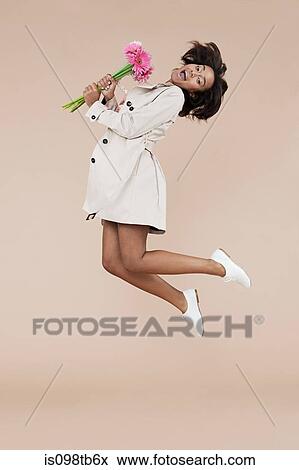 Young woman holding flowers and jumping View Large Photo Image Stock Photo - Young woman holding flowers and jumping. Fotosearch
