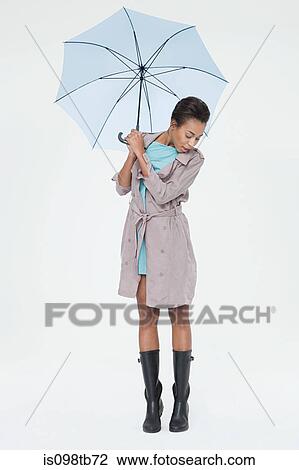 Young woman holding umbrella and looking down View Large Photo Image Stock Image - Young woman holding umbrella and looking down. Fotosearch