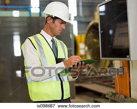 Stock Photo - Mature man inspecting factory equipment. Fotosearch