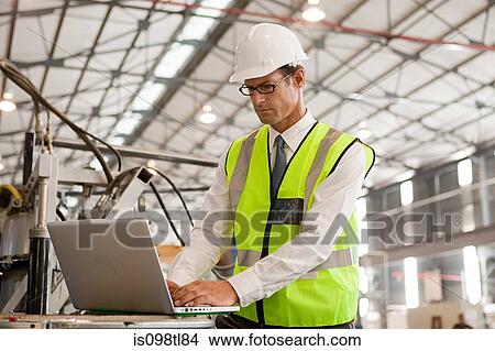 Mature man using laptop in factory View Large Photo Image Picture - Mature man using laptop in factory. Fotosearch