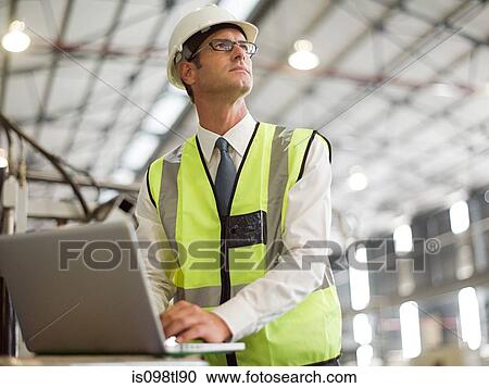 Mature man using laptop in factory View Large Photo Image Stock Image - Mature man using laptop in factory. Fotosearch