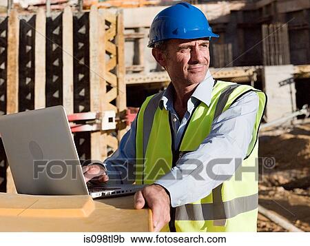 Mature man uusing laptop on construction site View Large Photo Image Stock Image - Mature man uusing laptop on construction site. Fotosearch