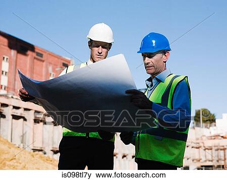 Mature men inspecting blueprints on construction site View Large Photo Image Stock Photo - Mature men inspecting blueprints on construction site. Fotosearch