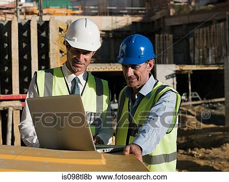 Mature men uusing laptop on construction site View Large Photo Image Stock Image - Mature men uusing laptop on construction site. Fotosearch