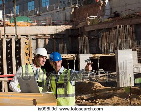Mature men uusing laptop on construction site View Large Photo Image Stock Image - Mature men uusing laptop on construction site. Fotosearch