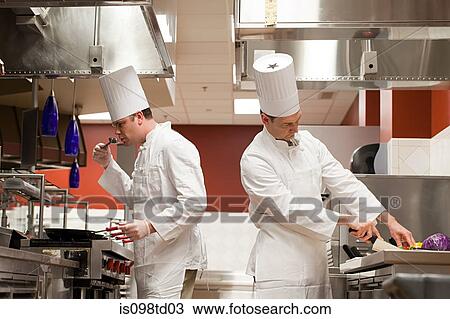 Stock Image - Chefs preparing food in commercial kitchen. Fotosearch