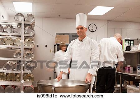 Stock Image - Chefs preparing food in commercial kitchen. Fotosearch