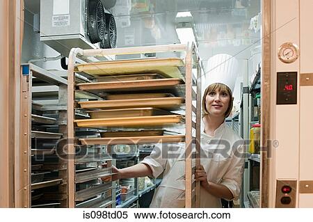 Stock Photography - Female chef in walk in freezer in commercial kitchen. Fotosearch