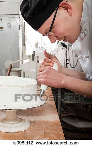 Male chef icing a cake in commercial kitchen View Large Photo Image Stock Image - Male chef icing a cake in commercial kitchen. Fotosearch