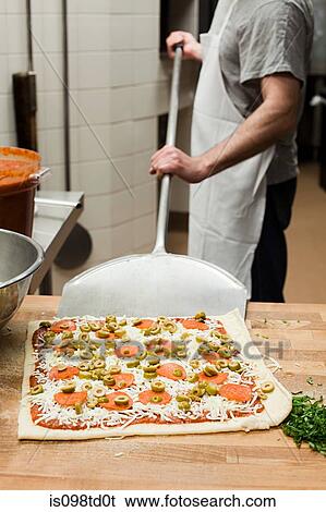 Stock Photograph - Male chef making pizza in commercial kitchen. Fotosearch